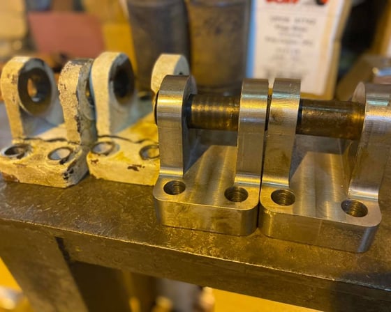 Worn original clevis blocks alongside freshly CNC-machined replacements at A&K Machine & Fabrication