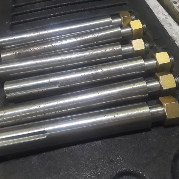 Row of finished bronze conveyor rollers with grooved profiles in a shipping case