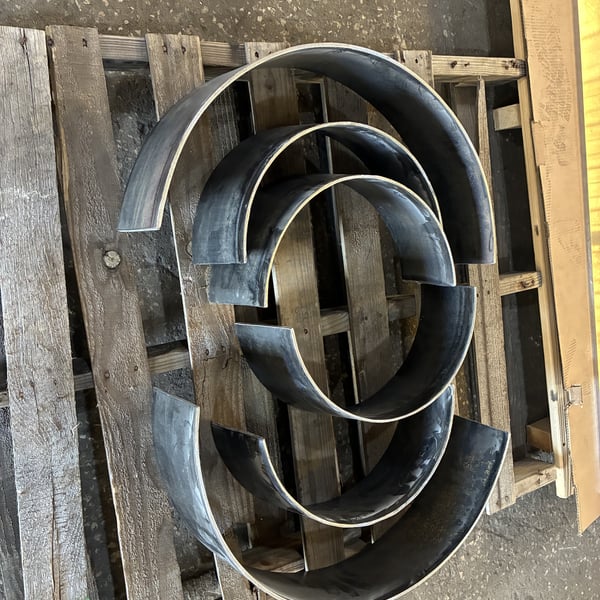 Stack of large-diameter rolled-and-welded steel rings on shop pallet