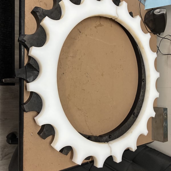 Custom UHMW conveyor sprocket alongside its black metal counterpart