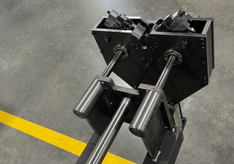 Custom precision cutter frame assembly with guide rods and V-housing on factory floor at A&K Machine & Fabrication