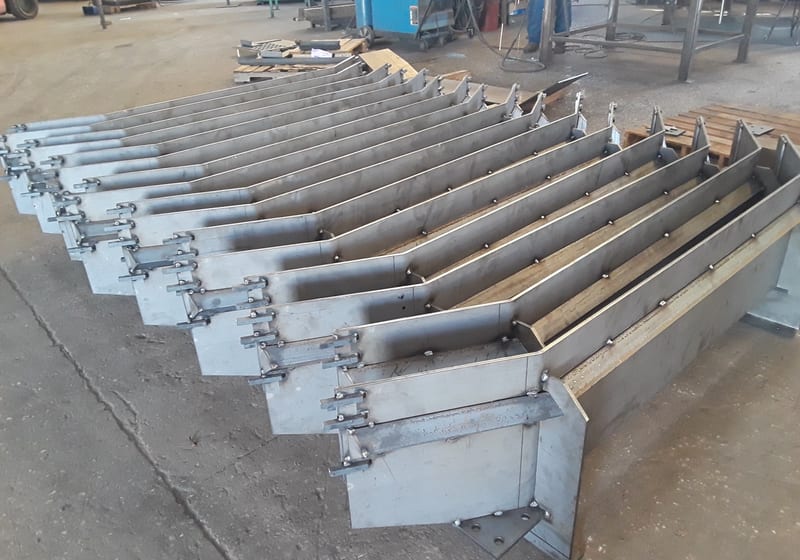 Row of long machined parts on workbench - batch production — A&K Machine & Fabrication, Jacksonville FL