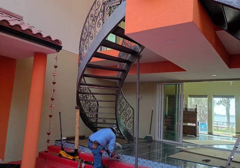 Ornate curved double staircase installed in red-walled foyer - finished install, dramatic — A&K Machine & Fabrication, Jacksonville FL