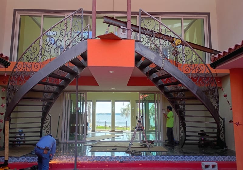 Ornate curved staircase from second-floor landing showing both flights - install context — A&K Machine & Fabrication, Jacksonville FL