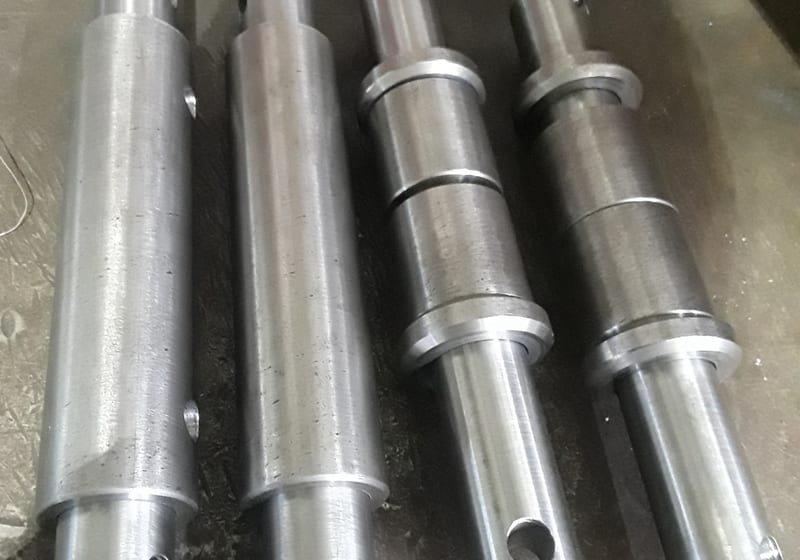 Three machined pinion shafts stacked on wood - heavy turn work — A&K Machine & Fabrication, Jacksonville FL