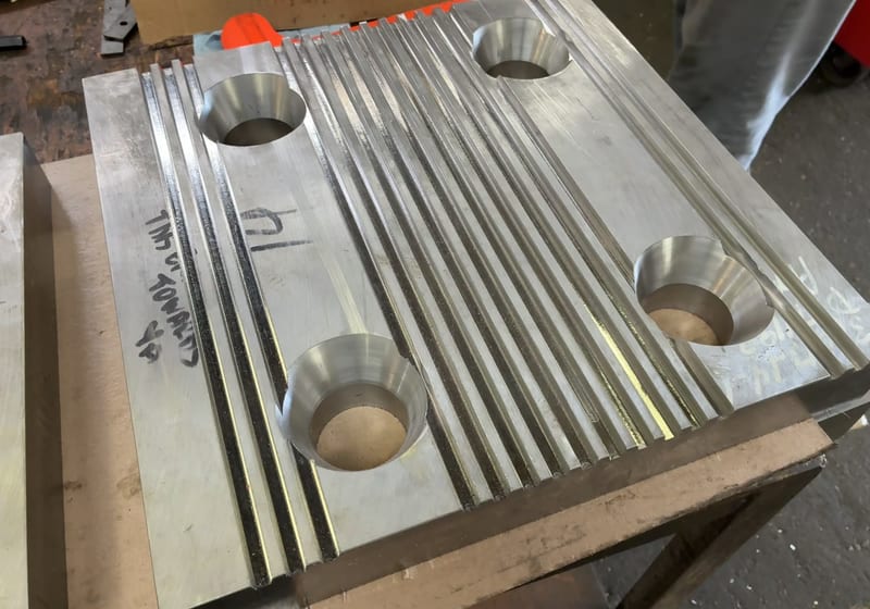 Ribbed steel baseplate with mounting bores - close-up of finished mill work — A&K Machine & Fabrication, Jacksonville FL