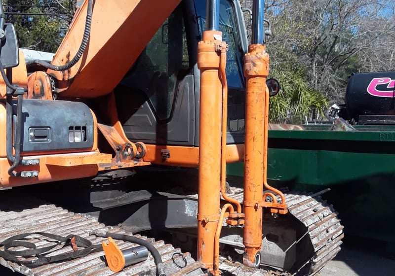 Worker servicing equipment outdoors with hydraulic tools - on-site work — A&K Machine & Fabrication, Jacksonville FL