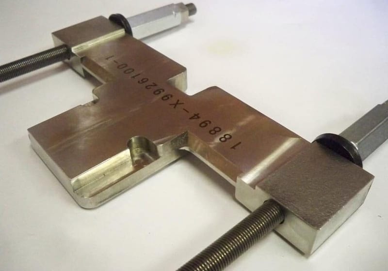 Precision-machined steel defense fixture with engraved part number at A&K Machine & Fabrication