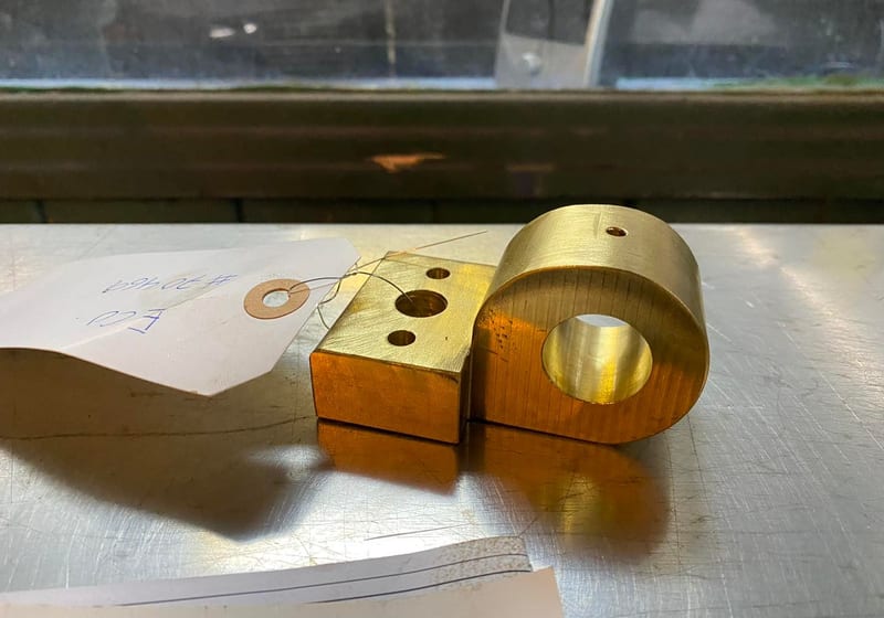 Custom-machined brass bearing block with drilled and tapped holes at A&K Machine & Fabrication