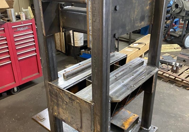 Heavy-duty welded steel machine base with vertical plates and mounting holes at A&K Machine & Fabrication