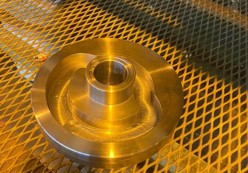 Machined bronze coupling with center bore and stepped profile at A&K Machine & Fabrication