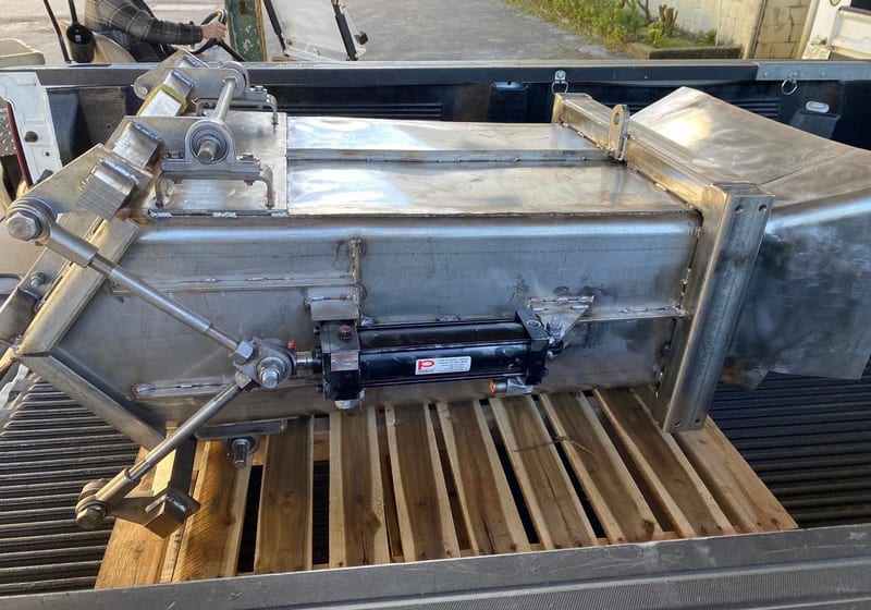 Custom stainless steel IBC chute with hydraulic cylinder on truck bed at A&K Machine & Fabrication