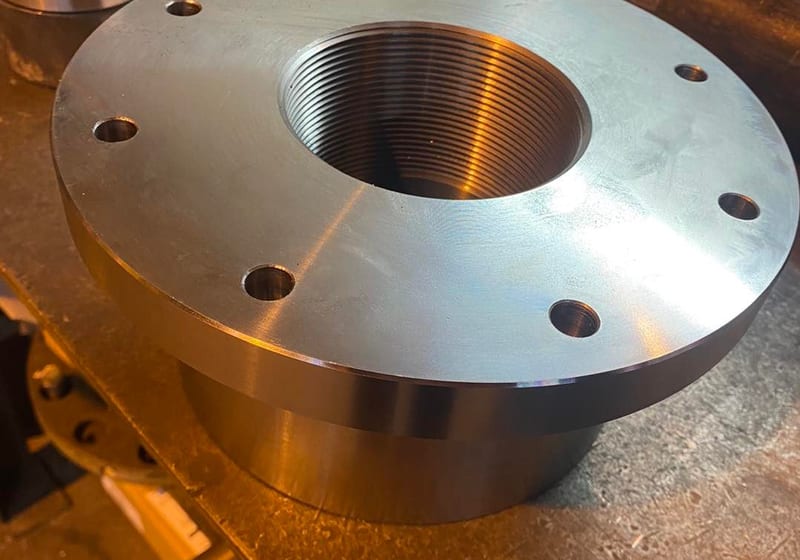 Large precision-machined steel NPT flange with internal threads and bolt holes at A&K Machine & Fabrication