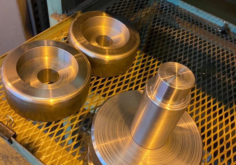 Three CNC-turned steel pulley roller adapters with flanged tops at A&K Machine & Fabrication