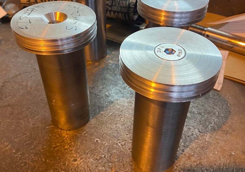 Three large CNC-turned steel pulley pins with flanged heads at A&K Machine & Fabrication