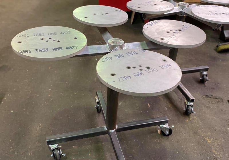 Custom-fabricated aluminum turntable stands with round plates on cross-base caster frames at A&K