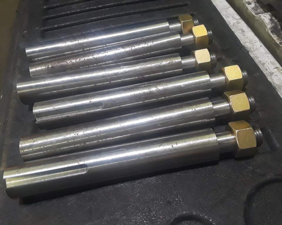 Row of finished bronze conveyor rollers staged and palletized for scheduled delivery — A&K Machine & Fabrication, Jacksonville FL
