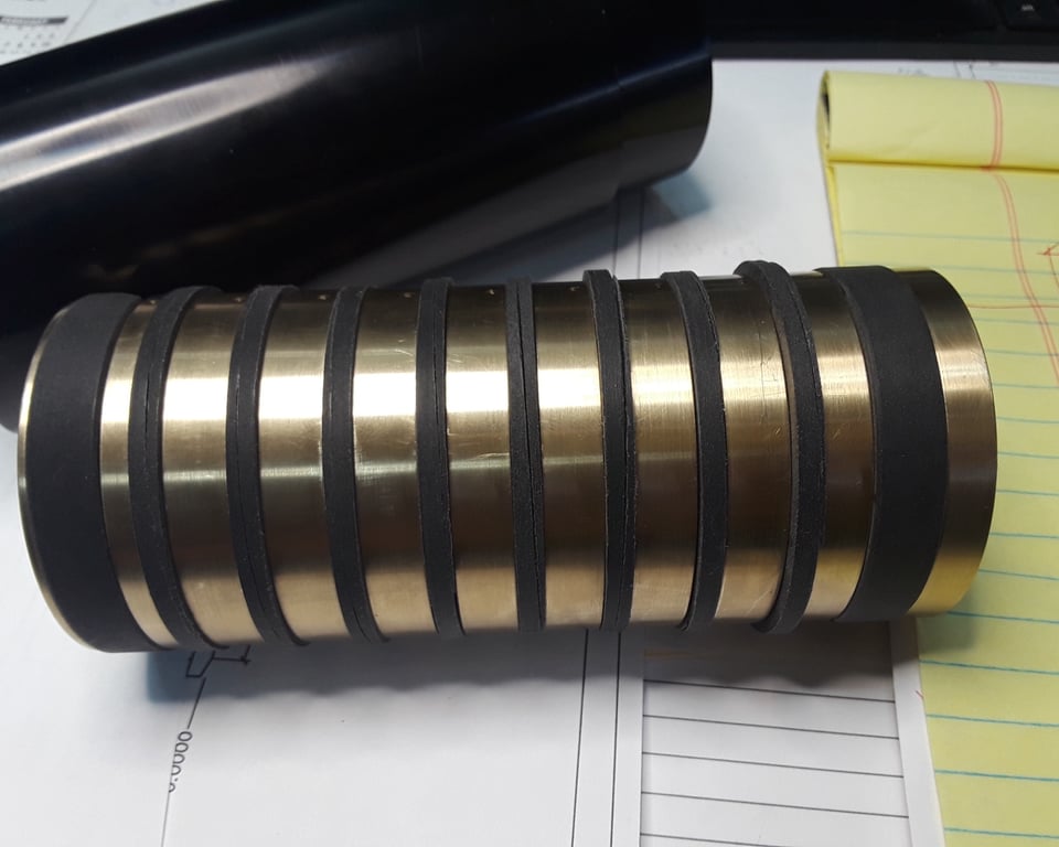 Black-coated finned roller drum with brass contact bands — custom-machined conveyor component by A&K Machine & Fabrication, Jacksonville FL