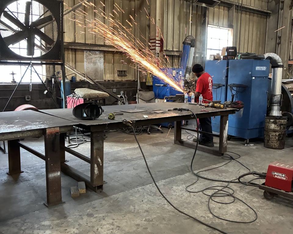 Welder grinding sparks on a steel beam in the A&K fabrication shop — A&K Machine & Fabrication, Jacksonville FL