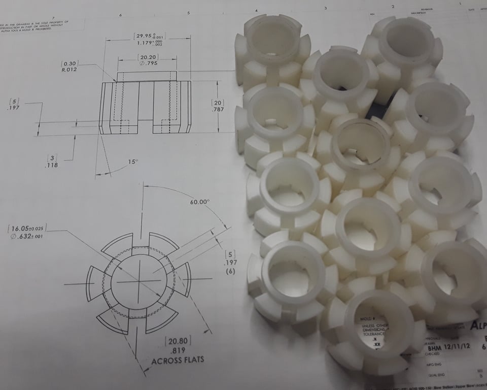 UHMW poly bushings laid on the engineering drawing they were machined from — print-to-part — A&K Machine & Fabrication, Jacksonville FL